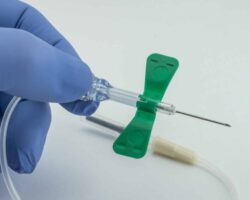 Nurse with blue glove holding a catheter of venipuncture